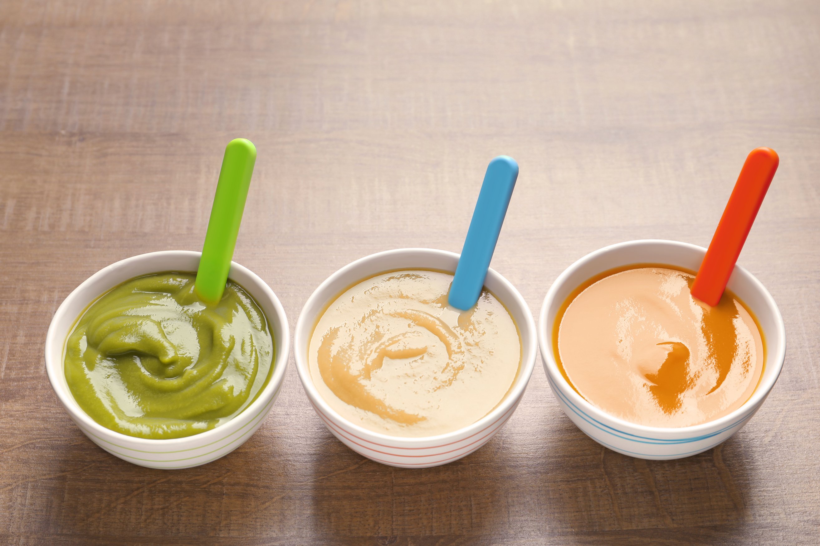 Assorted Bowls with Baby Food on Wooden Background